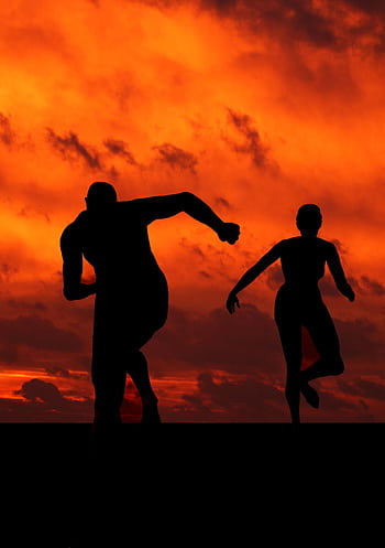 Silhouettes of male and female runners in action against a dramatic orange sunset. HD phone wallpaper