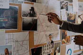 Detective examines a corkboard with maps and to solve a mystery. HD wallpaper