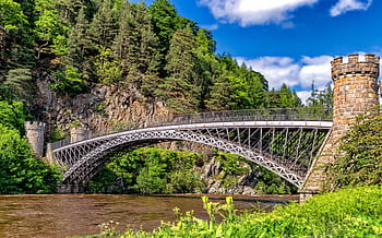 Scenic view of a historic bridge amidst lush greenery and rocky cliffs. HD wallpaper