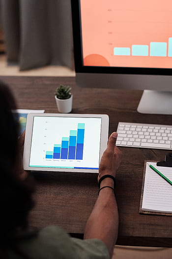 A person reviews statistical graphs on a tablet, showcasing data analysis and technology. HD phone wallpaper