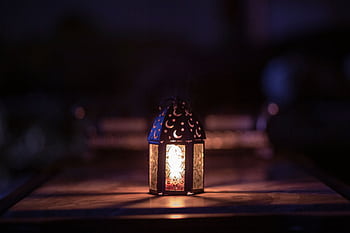 A beautifully decorated lantern illuminates a dark room, symbolizing Ramadan. HD wallpaper