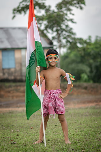 A young boy celebrates Indian Independence Day holding the national flag outdoors in Agartala. HD phone wallpaper