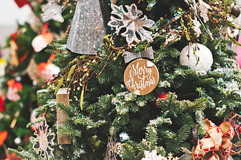Close-up of a beautifully decorated Christmas tree with festive ornaments and a Merry Christmas sign. HD wallpaper