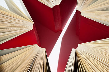 An artistic display of open books with red covers arranged in a star-like pattern. HD wallpaper