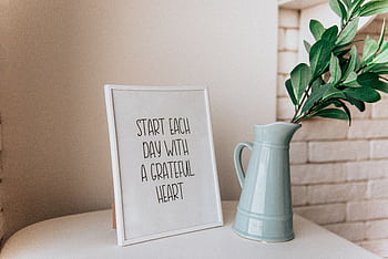 Framed quote 'Start each day with a grateful heart' next to a vase indoors. HD wallpaper