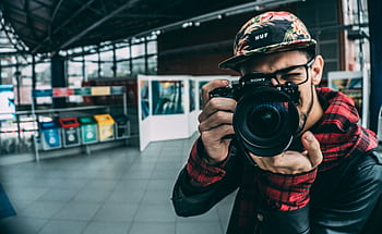 A young adult grapher with a DSLR camera indoors, highlighting modern graphy. HD wallpaper