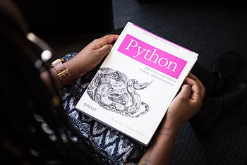A person reads 'Python for Unix and Linux System Administration' indoors. HD wallpaper