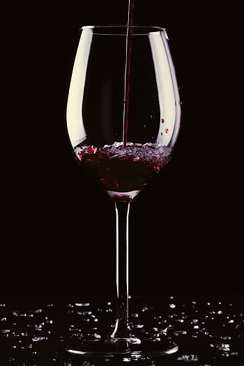 Close-up of red wine being poured into a clear crystal glass against a black background. HD phone wallpaper