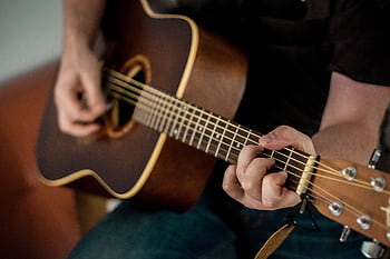 A musician strums chords on an acoustic guitar, showcasing musical talent. HD wallpaper