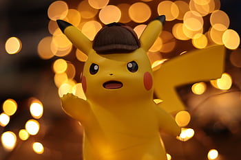 A close-up of a Pikachu figurine illuminated by a warm bokeh effect, creating an eye-catching visual. HD wallpaper