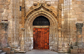 A detailed view of an intricately carved Gothic church door and stone arch. HD wallpaper