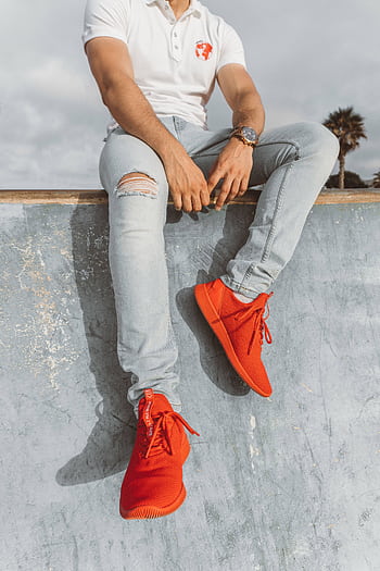 Man in vibrant red sneakers seated at a skate park in Rabat, Morocco. HD phone wallpaper