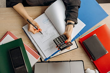 Accountant analyzing financial documents with a calculator on a desk, highlighting business tasks. HD wallpaper