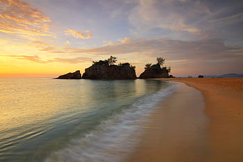 Tranquil beach scene at sunset with gentle waves and a scenic rocky outcrop. HD wallpaper