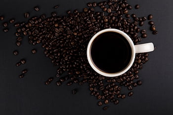 Flat lay of a white coffee mug with black coffee surrounded by roasted coffee beans. HD wallpaper