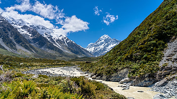 Landscape View Of Snow Capped Mountains Stones Rocks Bushes Trees River Blue Sky During Daytime Nature HD wallpaper