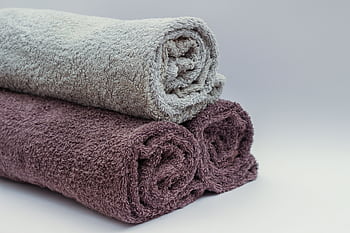 Close-up of rolled bathroom towels in neutral tones, ideal for interior design or spa themes. HD wallpaper