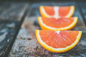Vibrant orange slices arranged on a rustic wooden table capturing a healthy lifestyle theme. HD wallpaper
