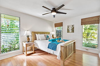 Sunny tropical bedroom with wooden furniture, teal accents, and lush greenery views. HD wallpaper