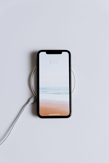 Minimalist smart on a wireless charger with a serene beach . HD phone wallpaper