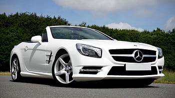 Stunning white Mercedes Benz convertible parked on the road against a lush green backdrop. HD wallpaper