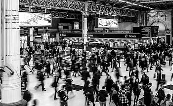 Dynamic black and white capturing a busy train station with a crowd of commuters. HD wallpaper