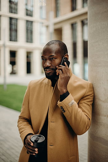 Elegant man in a trench coat talking on a smart outdoors. HD phone wallpaper