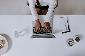Top view of a woman typing on a laptop at a modern, minimalist home office desk with plants. HD wallpaper