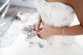 Bride in a dazzling wedding dress holding embellished high heels. HD wallpaper