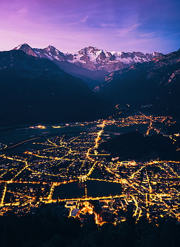 A mesmerizing aerial view of a beautifully lit town with majestic mountains in the twilight. HD phone wallpaper