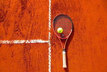 Tennis racket and ball on red clay court, ideal for sports-themed content. HD wallpaper