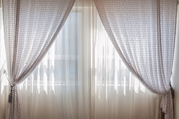 Sun shining through elegant white curtains in a cozy, modern interior setting. HD wallpaper