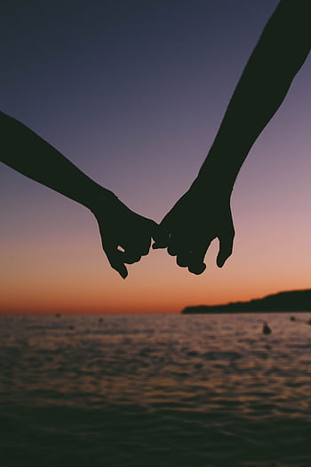 Silhouetted hands holding at sunset over a calm ocean. Romantic and peaceful seascape. HD phone wallpaper