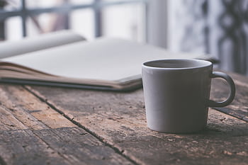 A mug of coffee on a rustic wooden table, perfect for a cozy moment or reading session. HD wallpaper