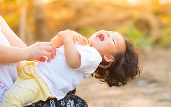 A happy baby enjoying playful moments outdoors, captured in warm summer lighting. HD wallpaper