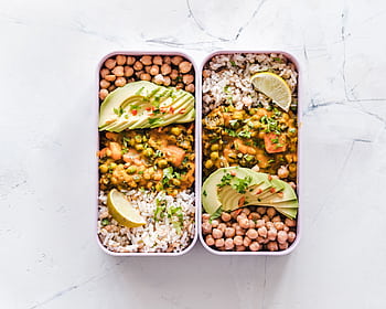 Delicious vegan lunchboxes featuring chickpeas, rice, avocado, and curry on a white background. HD wallpaper