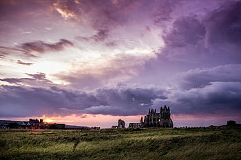 Explore stunning rural landscapes with a majestic castle ruin illuminated by a purple sunset sky. HD wallpaper