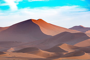 Capture the serene beauty of Namibian sand dunes under a vibrant sky. Perfect for desert-themed designs. HD wallpaper