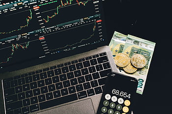 A laptop displaying stock charts with Bitcoin, Euros, and a cell calculator, showcasing financial analysis. HD wallpaper