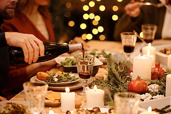 Warm holiday dinner setting with festive decorations, candles, and wine pouring for a joyful celebration. HD wallpaper