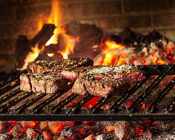 Succulent steaks grilling over hot coals and flames for a mouthwatering cookout. HD wallpaper