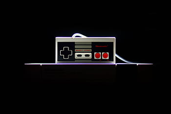 A close-up of a classic NES controller with dramatic lighting on a black background, evoking nostalgia. HD wallpaper