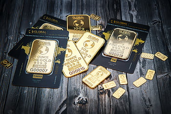 A collection of fine gold bars displayed on a textured wooden surface. HD wallpaper