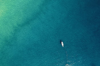Aerial view of a lone boat on calm turquoise waters, showcasing tranquility. HD wallpaper