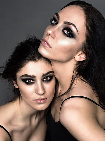 A striking studio portrait of two women posing with bold makeup and expressive eyes. HD phone wallpaper