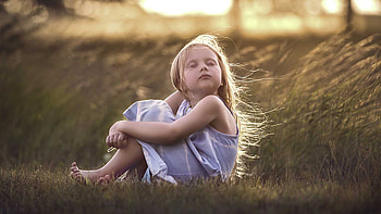 Cute Little Girl Is Closing Eyes Sitting On Grass Wearing Light Purple Dress In Blur Bokeh Background Cute HD wallpaper