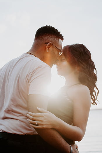 A couple embraces on a beach at sunset, capturing a moment of romance and affection. HD phone wallpaper