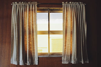 Warm sunlight streaming through fabric curtains in a wooden interior setting. HD wallpaper