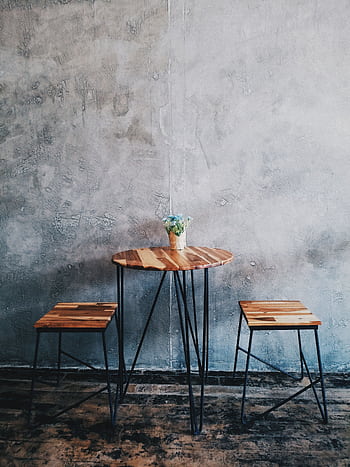 A minimalist wooden table with stools and a concrete wall background, ideal for modern interiors. HD phone wallpaper
