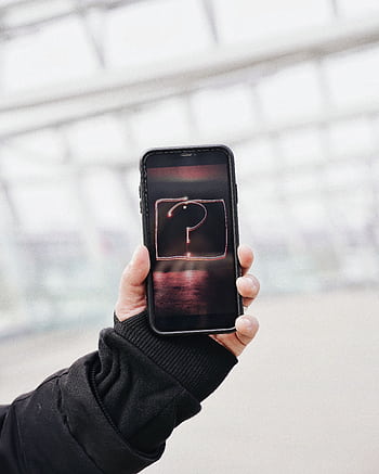 Close-up of a hand holding a smart showing a glowing question mark, symbolizing inquiry and technology. HD phone wallpaper